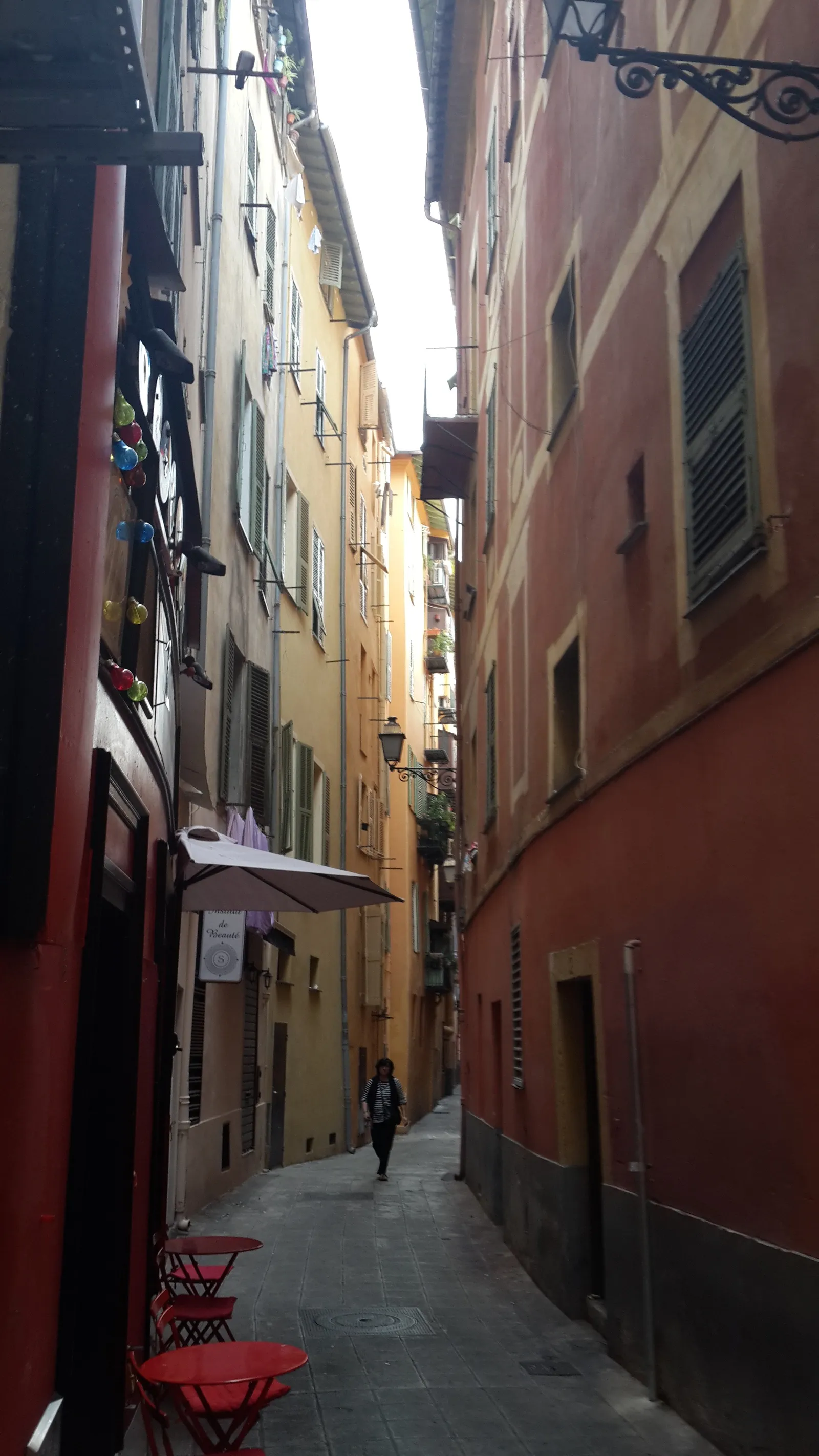 A narrow, colorful alley lined with red and yellow buildings in Nice's Old Town