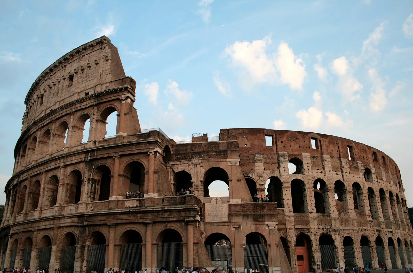 The Colosseum in Rome seen from outside, its ancient stone arches lit by late afternoon sun