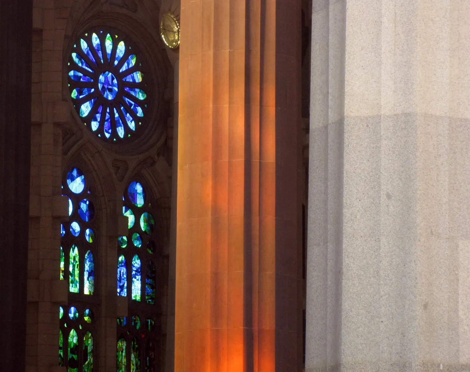 Sunlight through stained glass windows and tree-like columns inside the Sagrada Família