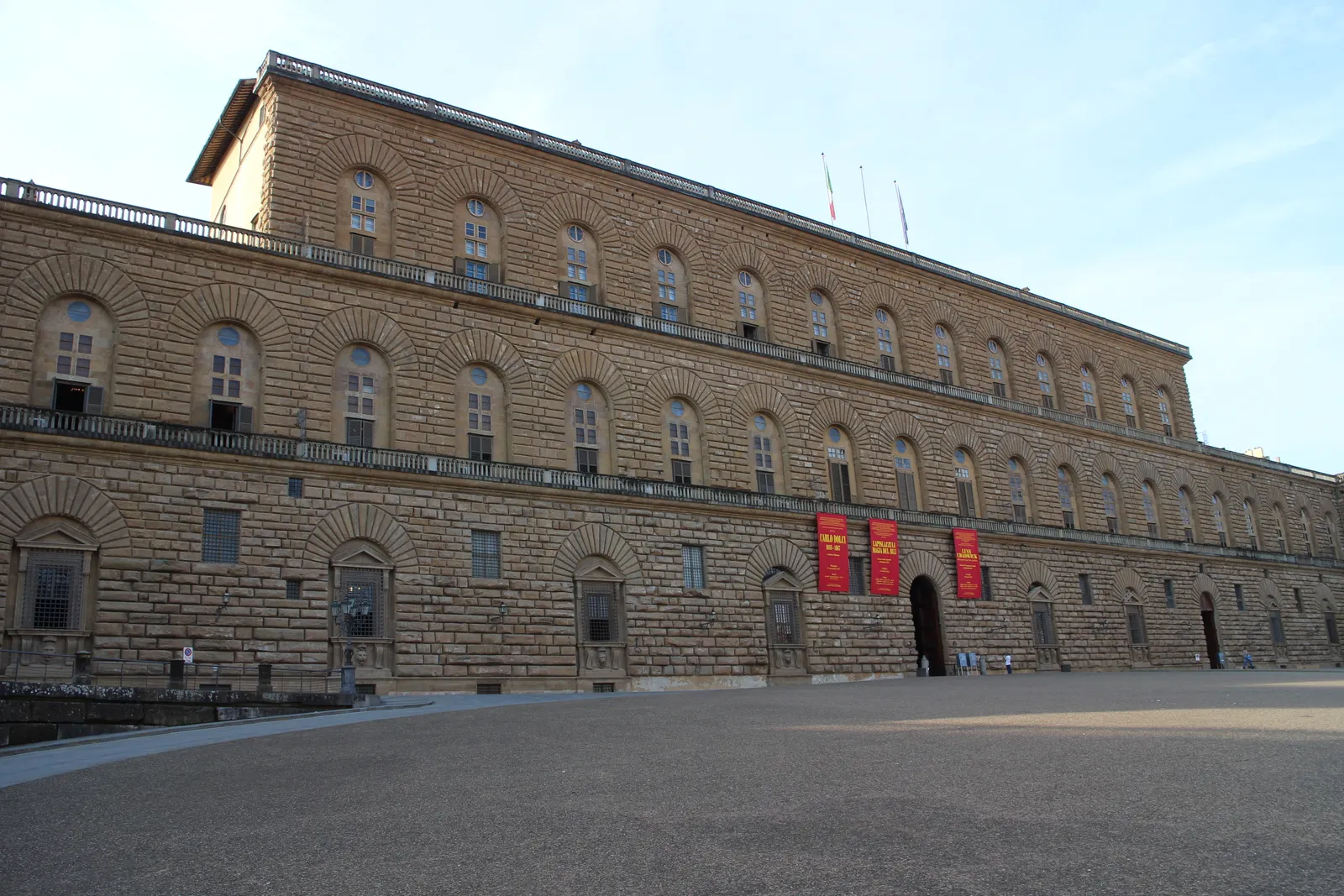 The massive rusticated stone facade of Palazzo Pitti in Florence under a clear sky