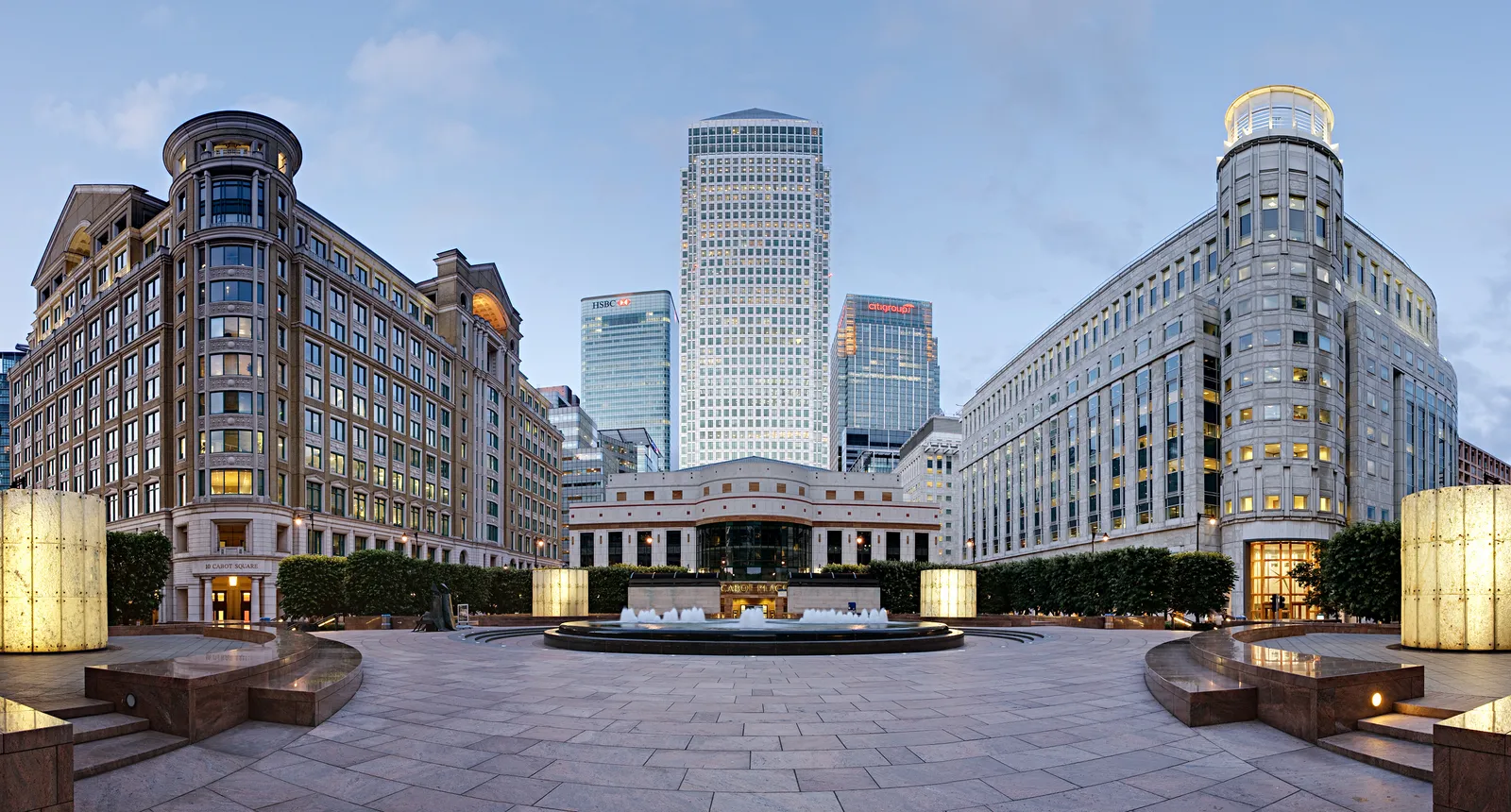 Cabot Square's fountain and surrounding office buildings lit up at dusk in Canary Wharf