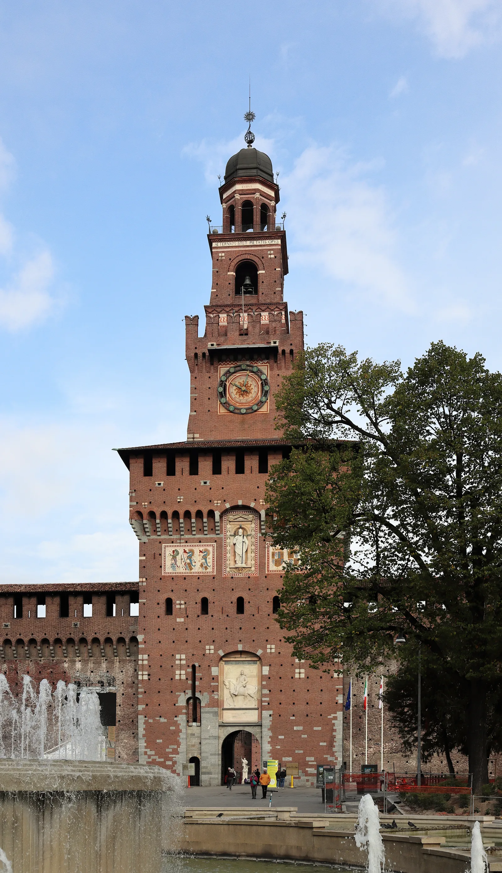 The brick Filarete Tower and main gate of Castello Sforzesco in Milan, seen across a fountain