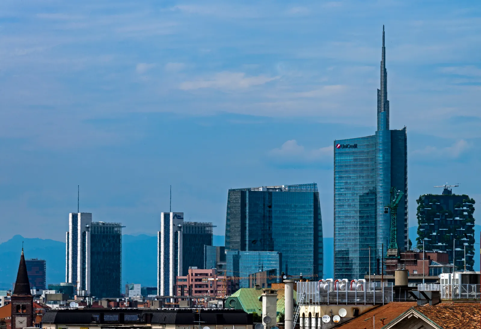 Milan's modern Porta Nuova skyline, including the UniCredit Tower's spire and the tree-covered balconies of the Bosco Verticale towers