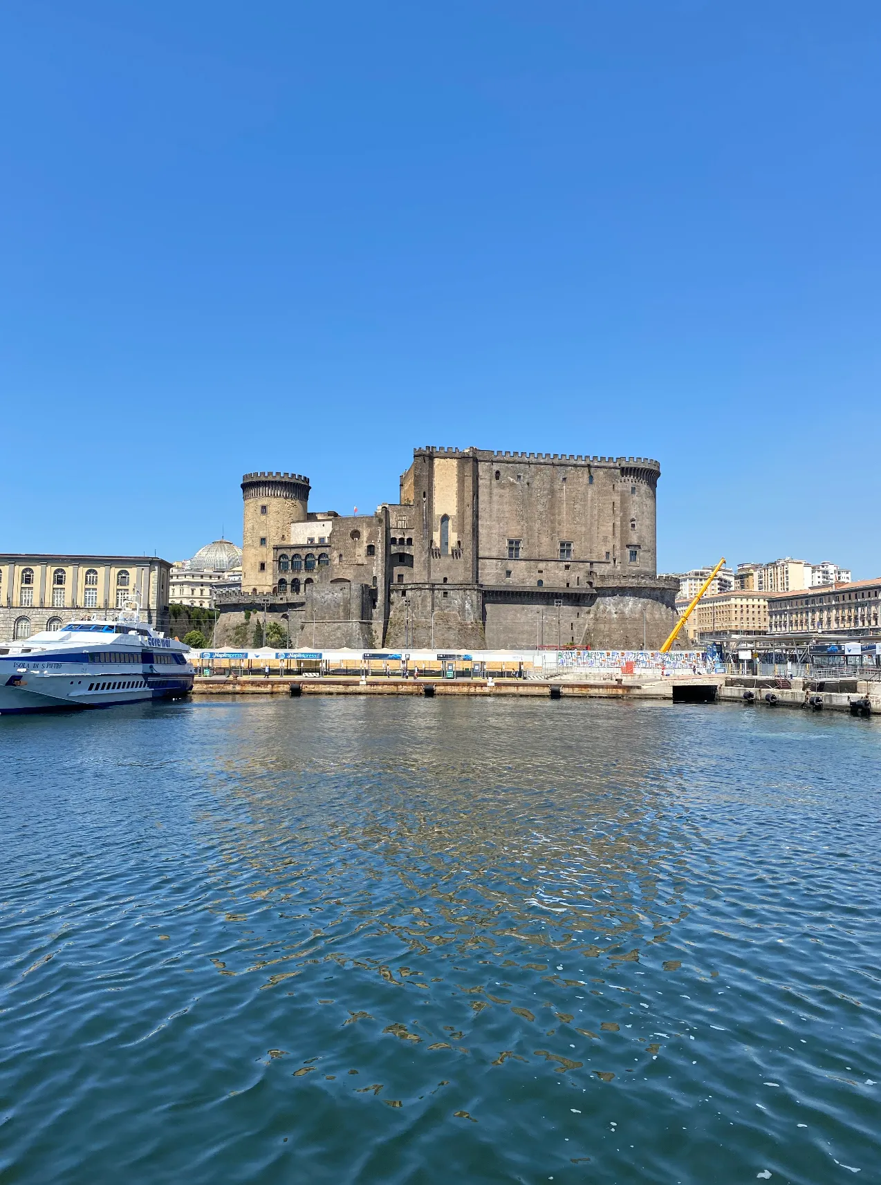A ferry docked at Molo Beverello in Naples with Castel Nuovo rising behind the harbor