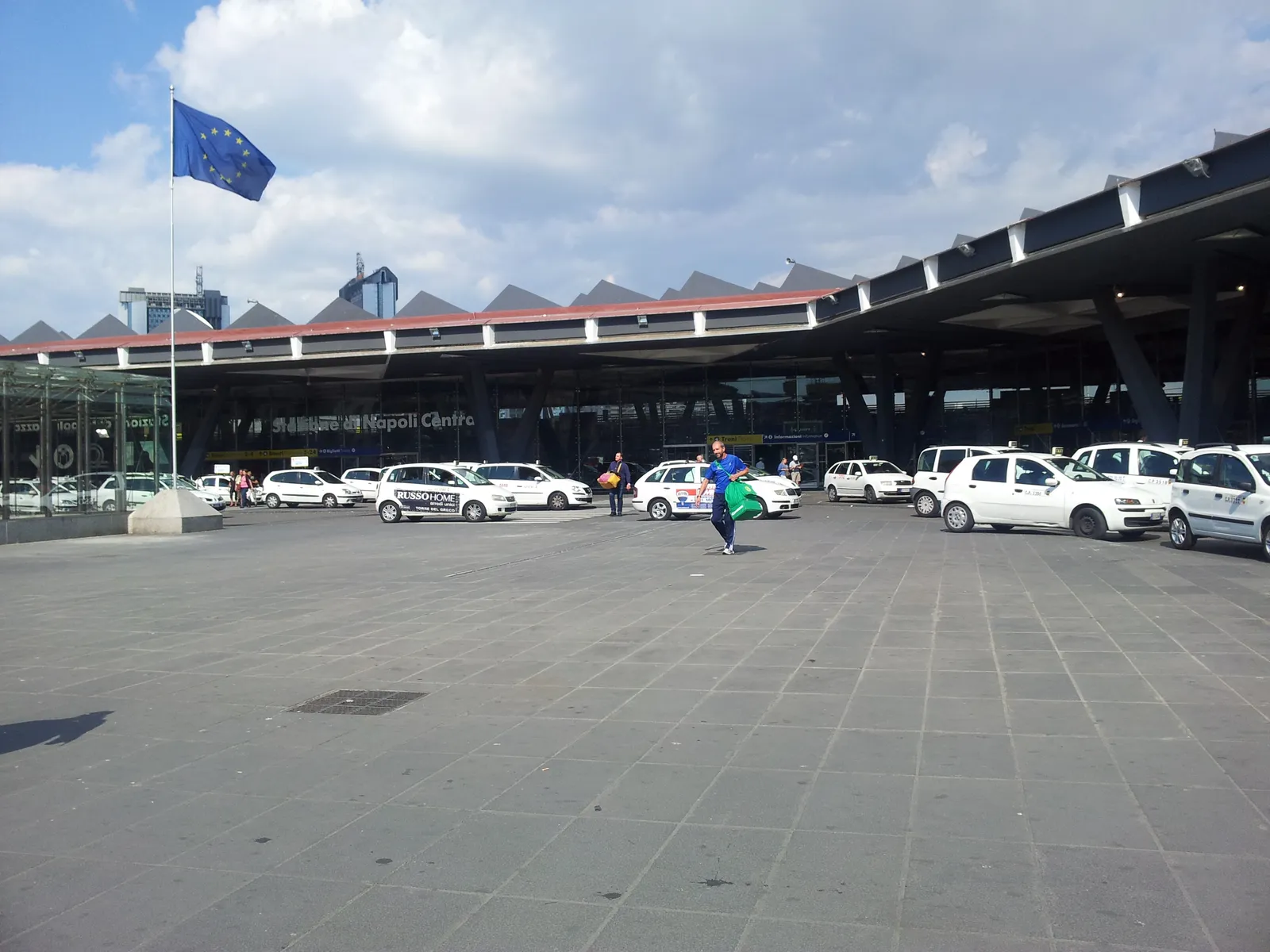 The modern facade and taxi forecourt of Napoli Centrale railway station in Naples