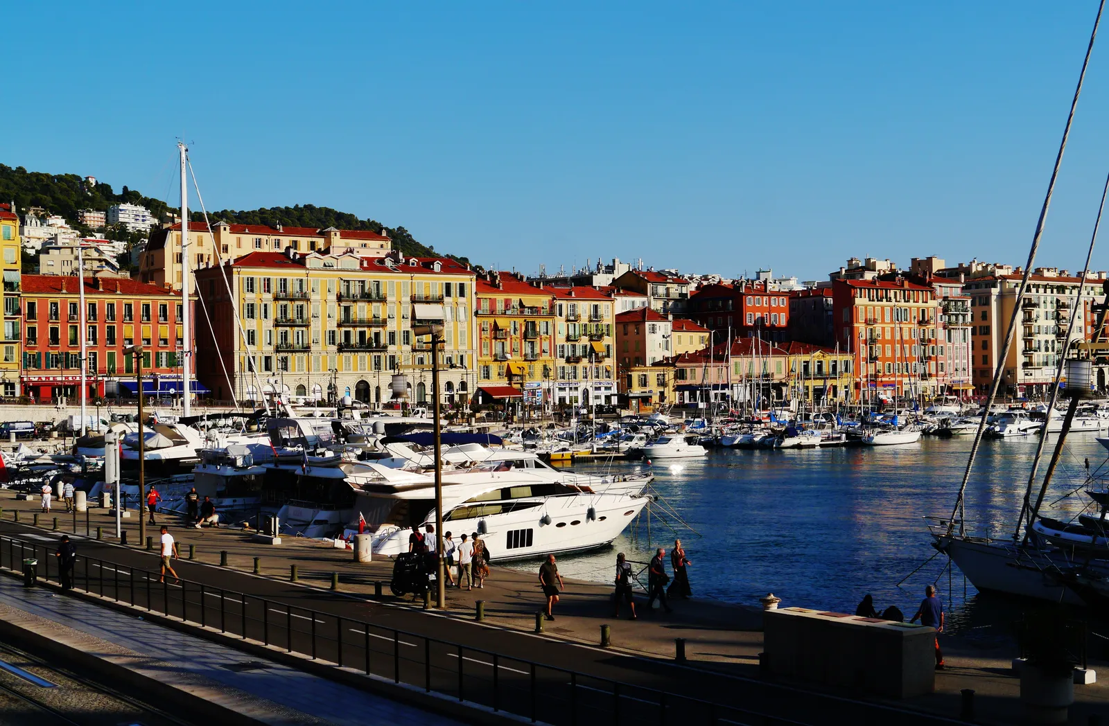 Yachts moored along the quay at Port Lympia in Nice, with rows of ochre and red harborside buildings behind