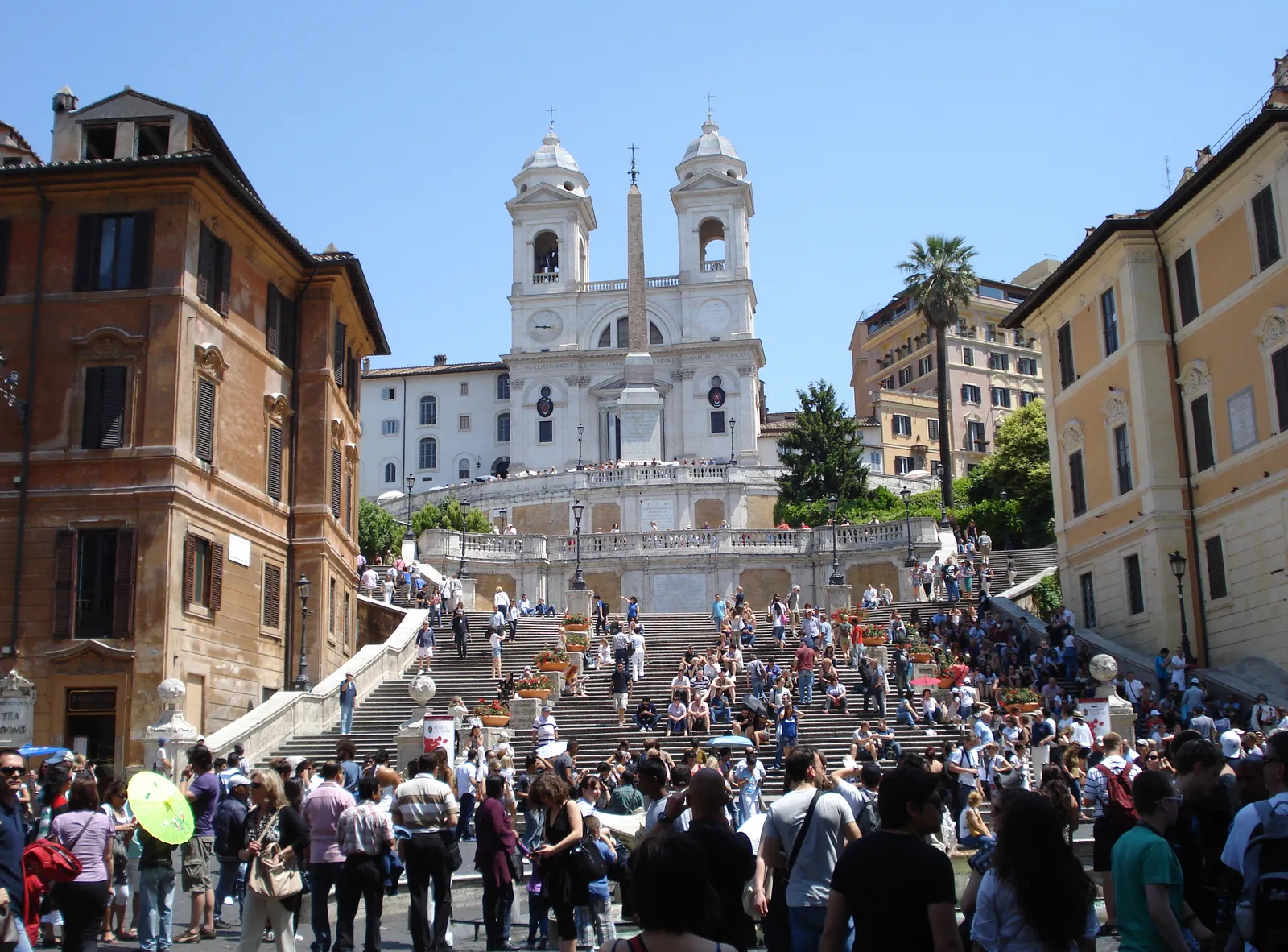 The Spanish Steps in Rome leading up to the Trinità dei Monti church and obelisk, crowded with visitors on a sunny day