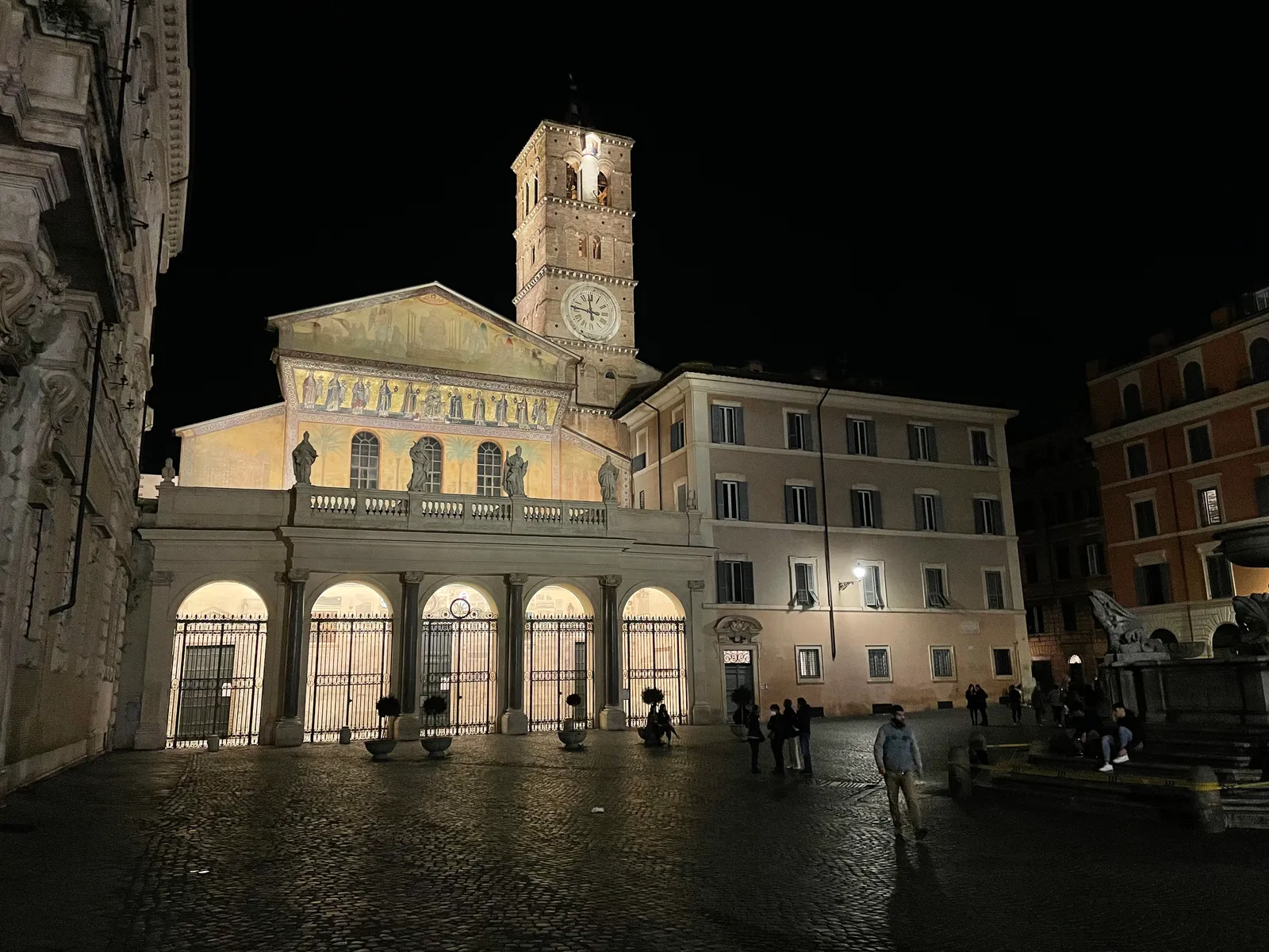 The gold-mosaic facade and bell tower of the Basilica di Santa Maria in Trastevere, lit up in the evening