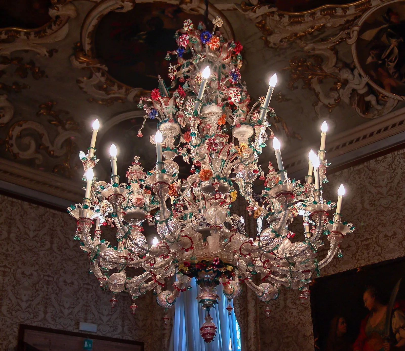 An ornate Murano glass chandelier with colorful glass flowers, an example of the island's traditional glassmaking craft, photographed at Ca' Rezzonico in Venice